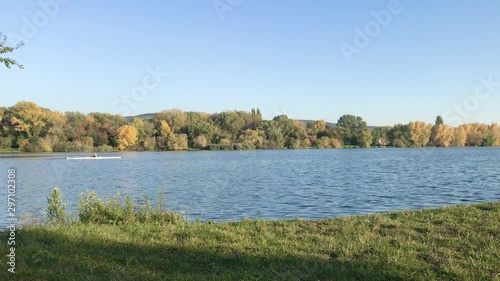 Man paddling canoe in lake Slnava in Piestany, Slovakia. Kayaking, canoeing, paddling. Kayaking in the water in sunny autumn day. Bright blue sky. photo