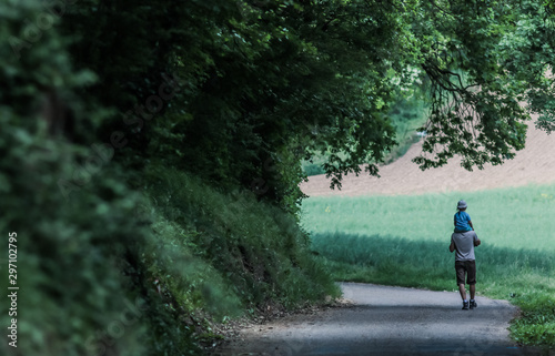 papa portant sa fille sur ses épaules sur une route de campagne