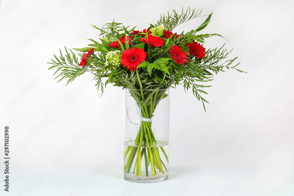 Obraz premium Different types of flowers arranged in a glass vase on a completely white background