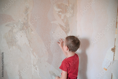 Home renovation, room wall repairing, young boy removing old wallpaper