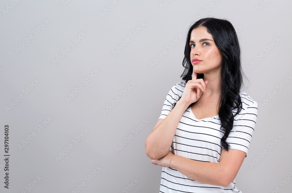 Young woman in a thoughtful pose on a gray background