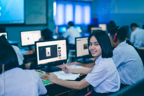 Smiling Asian female high school student in white uniform is enjoying social media in computer room. © pop_thailand