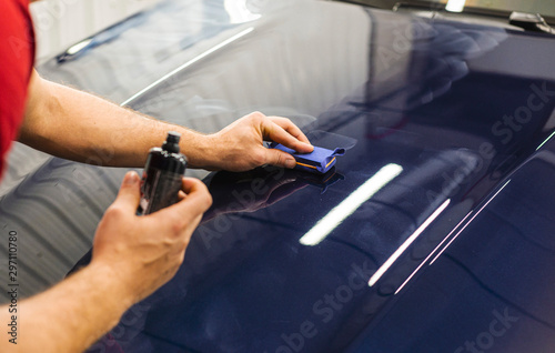 Car Detailing - A man is applying a nanoprotective coating to a car. A professional ceramic stacker applies different layers to the machine with an applicator sponge. Concept from  Auto Detailing