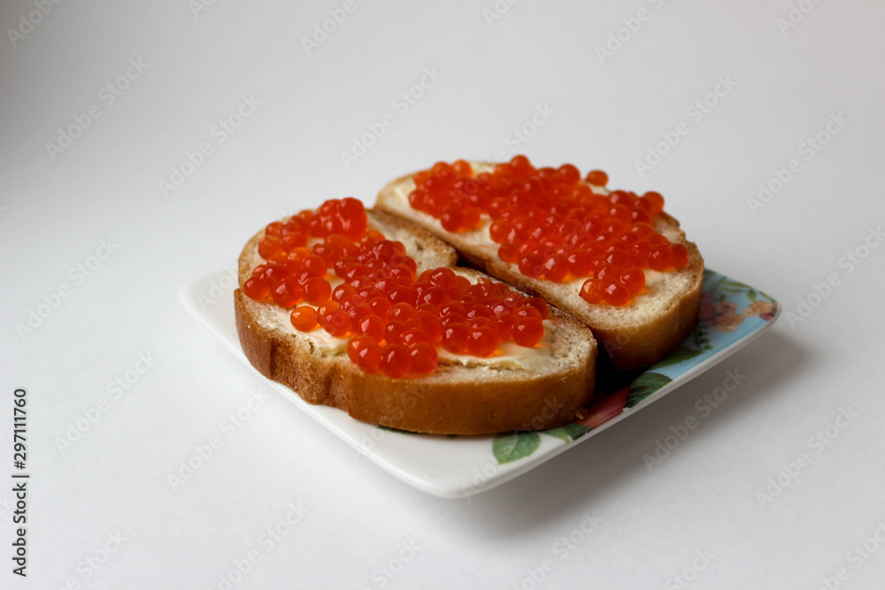 Two sandwiches with red caviar on a plate with flowers