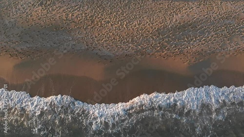 Aerial bird's eye view shot of wave crashing on beach in slow motion. Amolofoi Greece photo