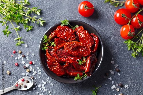 Sun dried tomatoes with fresh herbs and spices. Slate background. Top view.