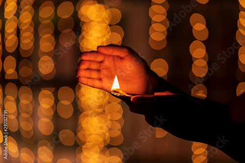 Female Holding Diya Celebrating Diwali. Young woman holding diya, clay oil lamp during Diwali festival. Concept for traditional diwali, holiday festive season background with copy space.
