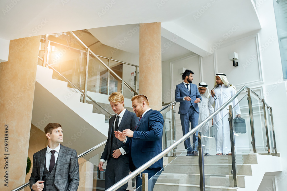 Caucasian men go speaking, having conversation after conference with sheikhs. Business center background Caucasian men go speaking, having conversation after conference with sheikhs. Business center background