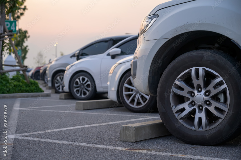 Many cars are parked in a large parking lot. Arranged in a long line Was the time when the sun was setting