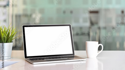 Workspace with laptop computer, coffee mug and plant pot.