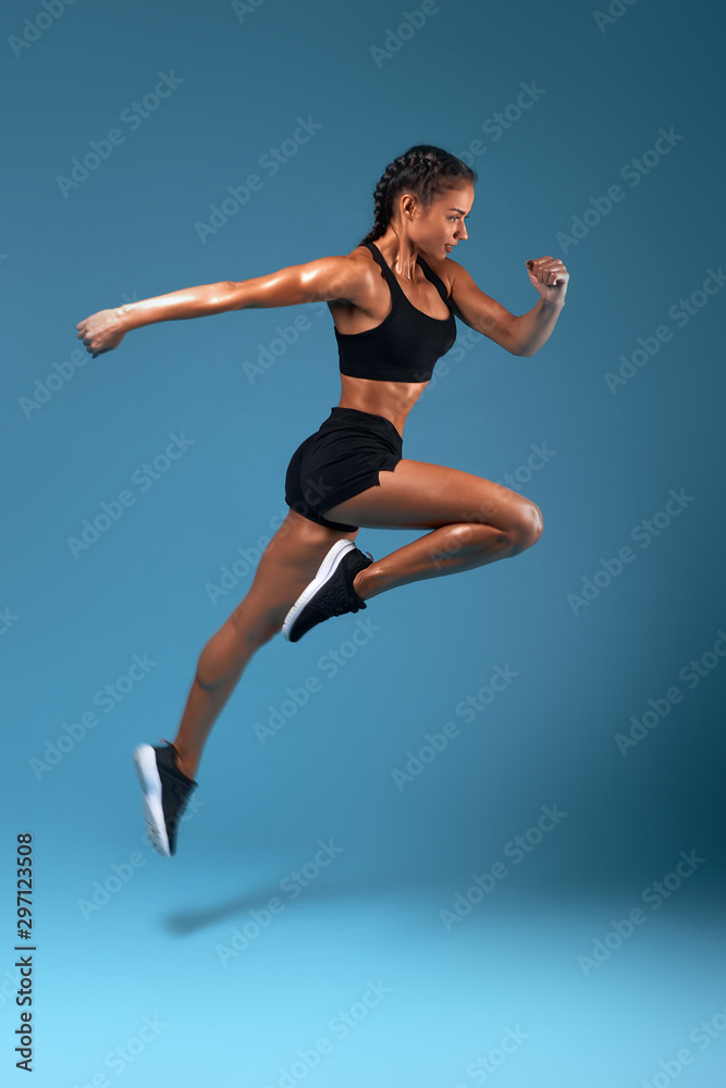 professional athlete training at sport center, full length side view photo. isolated blue background, studio shot.health and body care, wellness, woman is running to her dream