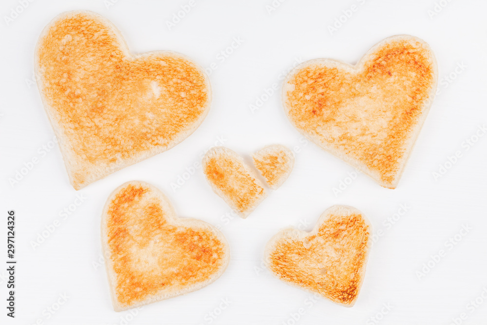 Group of toasted bread hearts with one broken heart together on white background. The concept of support in big family. Group of toasted bread hearts with one broken heart together on white background. The concept of support in big family.