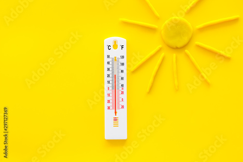 Sunny weather concept. Sun and thermometer on yellow background top view copy space