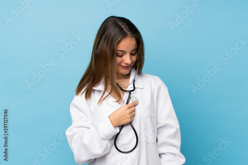 Tableau sur toile Young brunette girl over isolated blue background with doctor gown