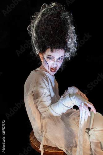 studio shot portrait of young girl in costume dressed as a Halloween, cosplay of scary bride of Frankenstein pose on isolated black background