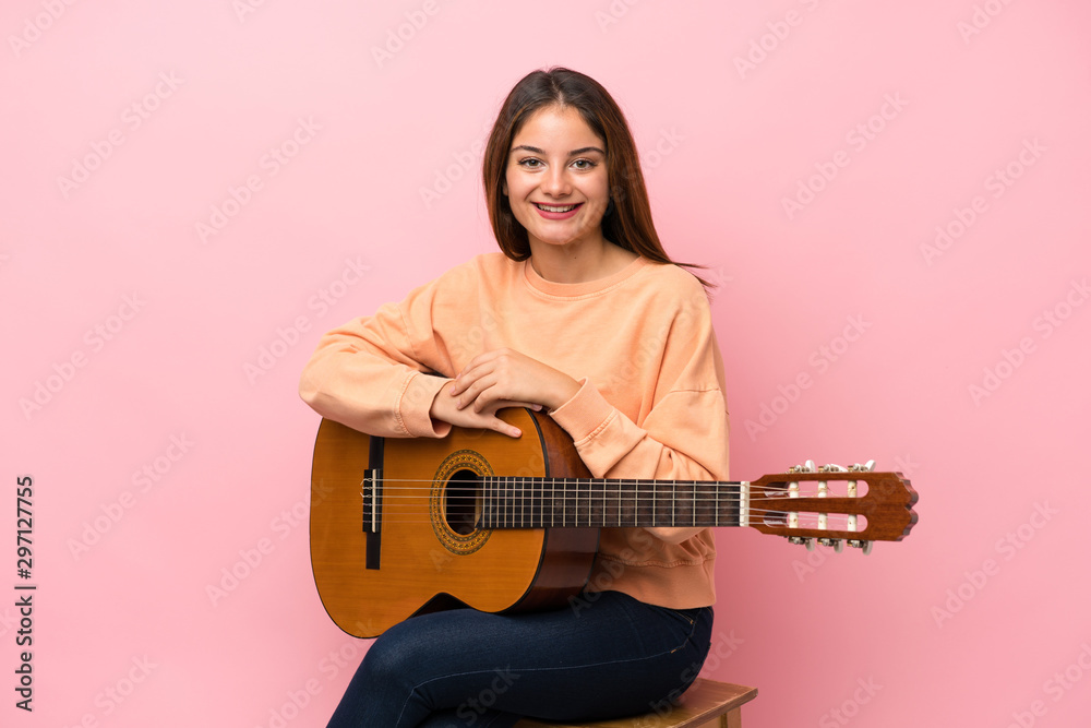 Young brunette girl with guitar over isolated pink background smiling a lot Young brunette girl with guitar over isolated pink background smiling a lot