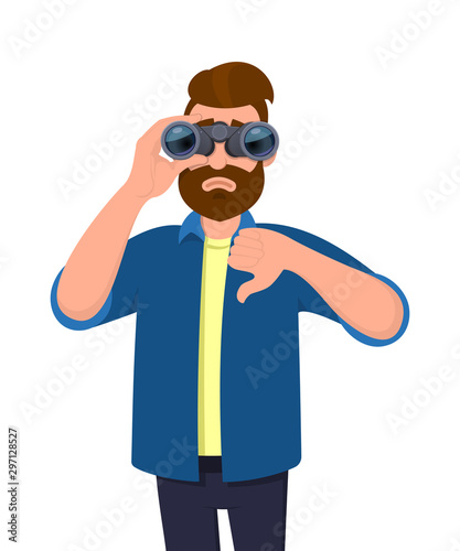 Unhappy young man looking in the distance through binoculars and gesturing, making thumbs down sign with hand finger. Person is seeing from binocular. Modern lifestyle, bad, negative, dislike concept.