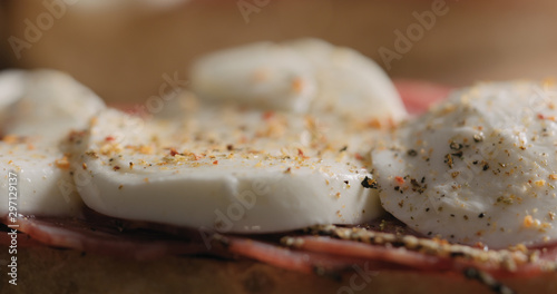 Extreme closeup freshly ground spices on salami mozzarella sandwich