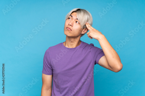 Young asian man over isolated blue background with problems making suicide gesture