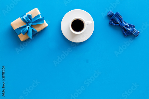 Greeting card for men's birthday. Present box, bow tie and coffee on blue background top view frame copy space photo