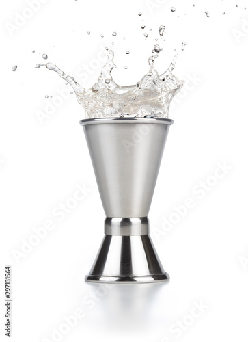 alcohol splashing out of a steel jigger isolated on white
