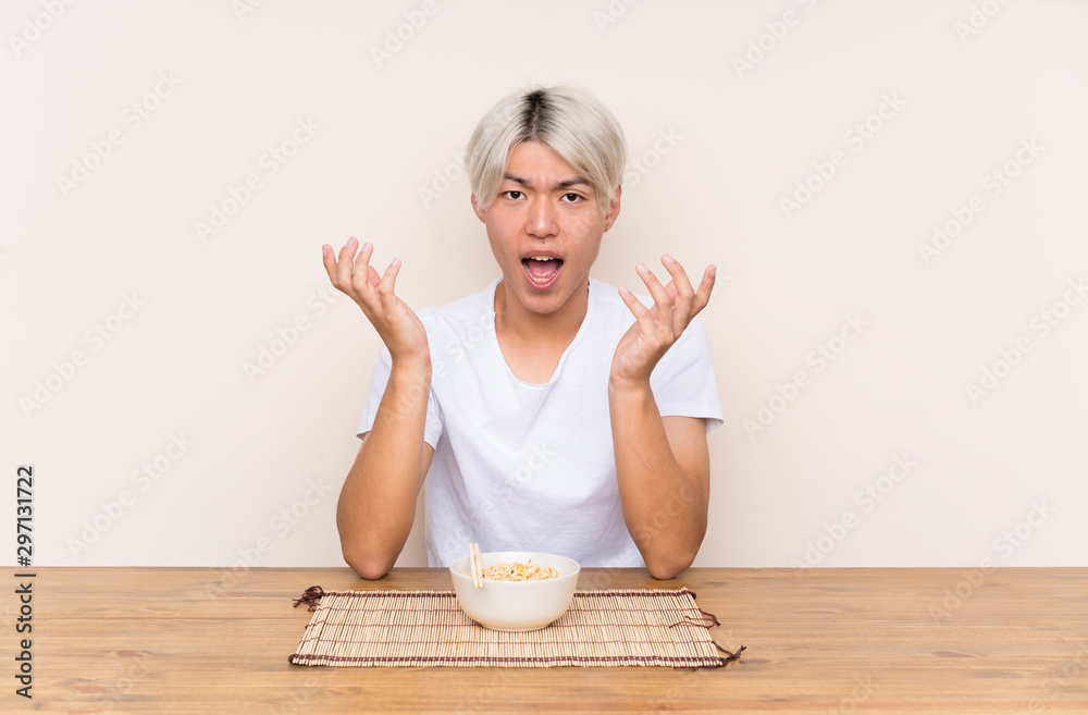 Young asian man with ramen in a table unhappy and frustrated with something Young asian man with ramen in a table unhappy and frustrated with something