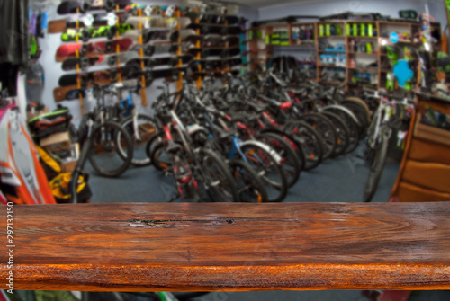 Mockup. Image of sport store with bike. Defocused, blurred image. In the foreground is the top of a wooden table, counter.