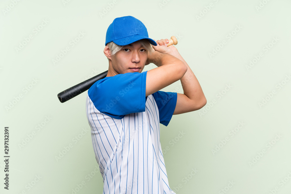 Young asian man playing baseball over isolated green background