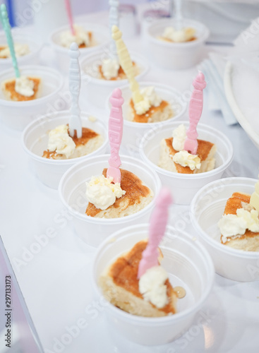 Food free sample. A small bite piece of souffle pancakes with fresh cream in small plastic takeaway cup for customers to try. Soft focus on the pancake with pink toothpick.