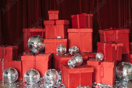 A large group of gift wrapped Christmas presents in colorful red wrapping paper with ribbons and bows, on a red background with c and metaphane. Gift photozone photo