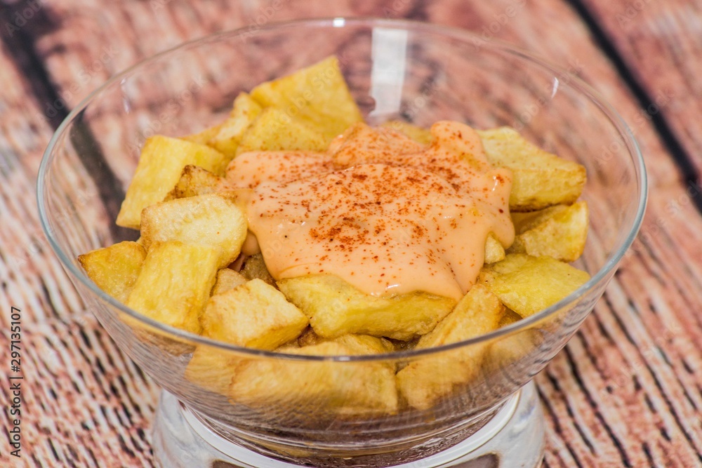 Plate of spanish potatoes with spicy sauce on a glass container Plate of spanish potatoes with spicy sauce on a glass container