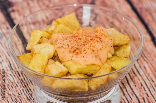 Plate of spanish potatoes with spicy sauce on a glass container