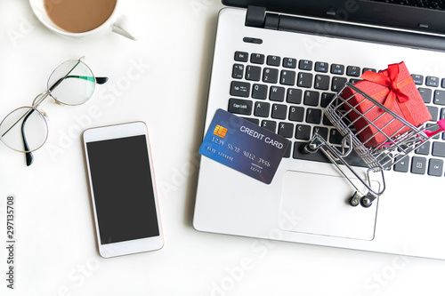 Online shopping concept. Shopping cart, small box, laptop, mobile phone, credit card on the desk at home. top view, copy space