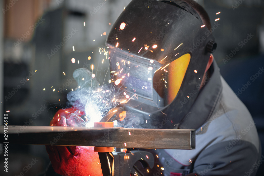 Welder is welding a metal frame. - obrazy, fototapety, plakaty 