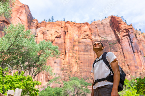 Zion National Park Riverside walk trail road in Utah with man hiker looking up with backpack on red canyon cliff formations hiking towards narrows