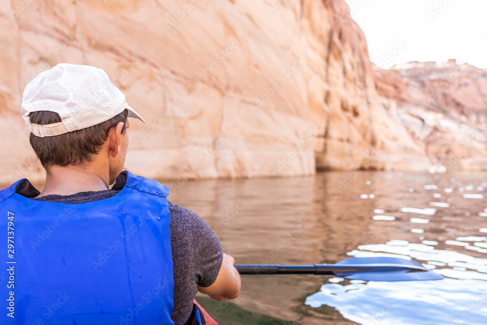 Back of man swimming kayaking in Lake Powell water antelope canyon with paddle oar and life jacket vest