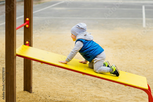 Two-year-old brightly dressed boy is playing on the playground