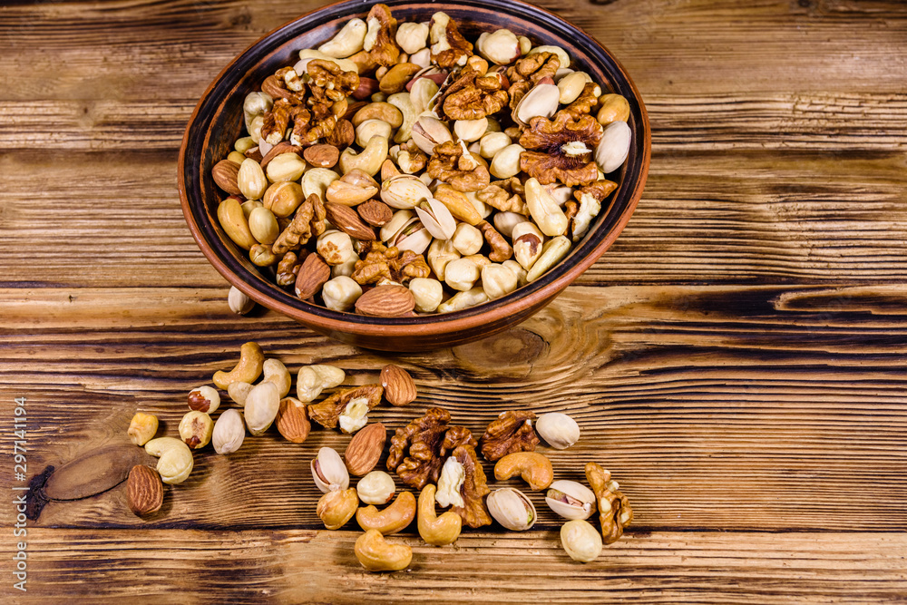 Various nuts (almond, cashew, hazelnut, pistachio, walnut) in ceramic plate on a wooden table. Vegetarian meal. Healthy eating concept Various nuts (almond, cashew, hazelnut, pistachio, walnut) in ceramic plate on a wooden table. Vegetarian meal. Healthy eating concept