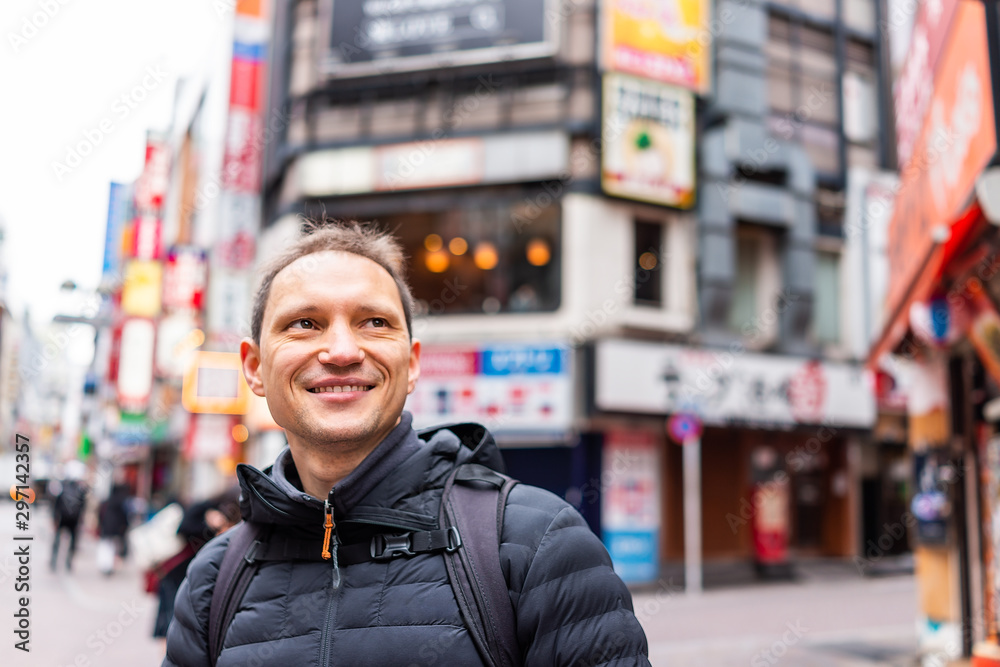 Tokyo, Japan Shibuya district and happy man tourist closeup in famous Koen dori shopping street in downtown city with colorful architecture in bokeh background Tokyo, Japan Shibuya district and happy man tourist closeup in famous Koen dori shopping street in downtown city with colorful architecture in bokeh background
