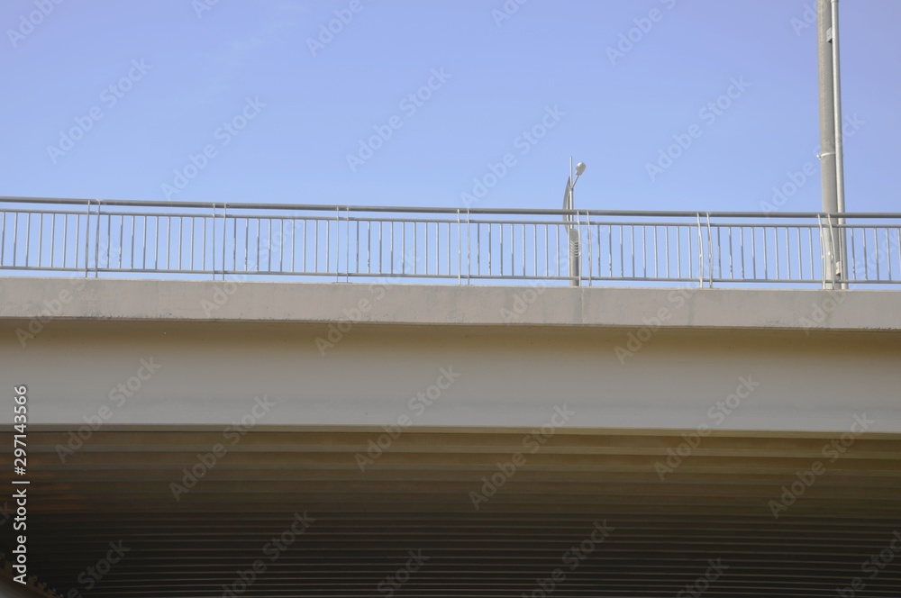 Fototapeta premium Close - up of a concrete bridge, against the blue sky, side view. Visible railing.