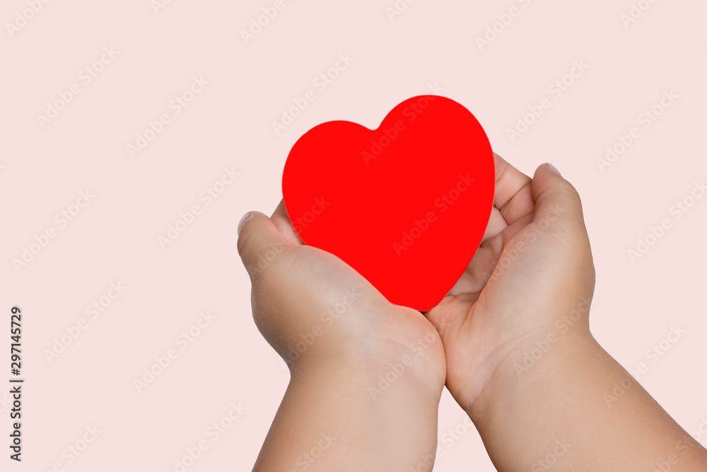 Red heart in the hands of a child on a pink background, the concept of donation of donated blood. Red heart in the hands of a child on a pink background, the concept of donation of donated blood.