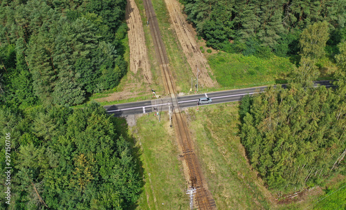 Obraz na plátně Aerial drone perspective view on railroad crossing with asphalt road in the fore