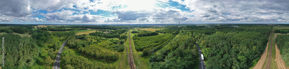 Aerial drone wide panoramic view on straight and curved railroad and asphalt road in natural scenery with green forest, cargo truck on the way. Aerial drone wide panoramic view on straight and curved railroad and asphalt road in natural scenery with green forest, cargo truck on the way.