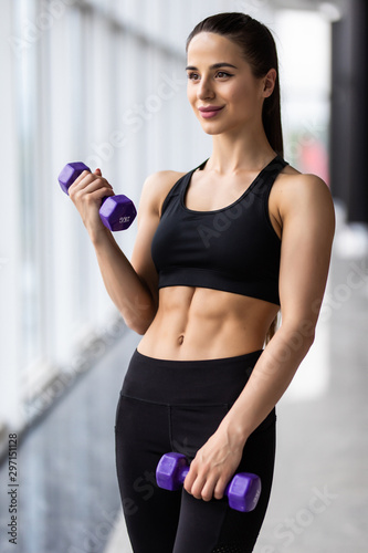 Young fitness girl holding a dummbell at gym photo