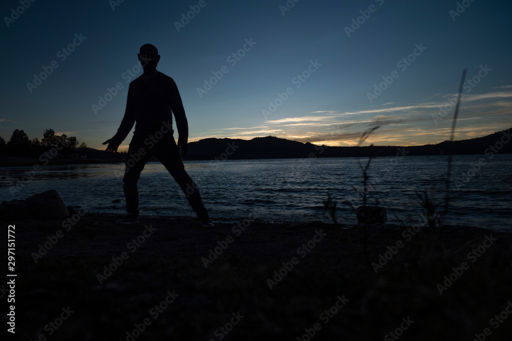 Fototapeta premium silhouette of a man during sunset next to lake