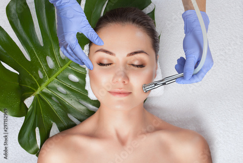 The cosmetologist makes the  Microdermabrasion procedure of the facial skin of a woman in a beauty salon.Cosmetology and professional skin care. photo