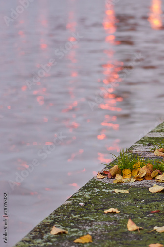 Promenade of Aurariver in Turku, Finland with yellow autumn leaves and blurred water of river with lights on a background.