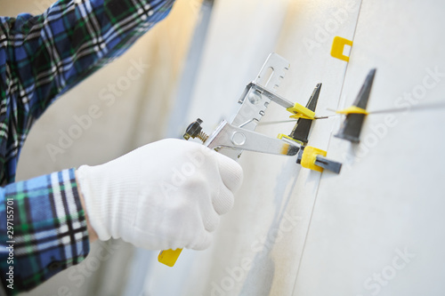 Tiler installing large format tile on wall. tile leveling system