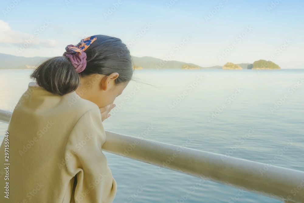 Asian young girl stands on baluster of ferry for relaxing and look at the ocean and island Asian young girl stands on baluster of ferry for relaxing and look at the ocean and island