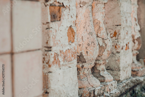 Pale pink cracked old fence columns of a building. © Ira_Shpiller